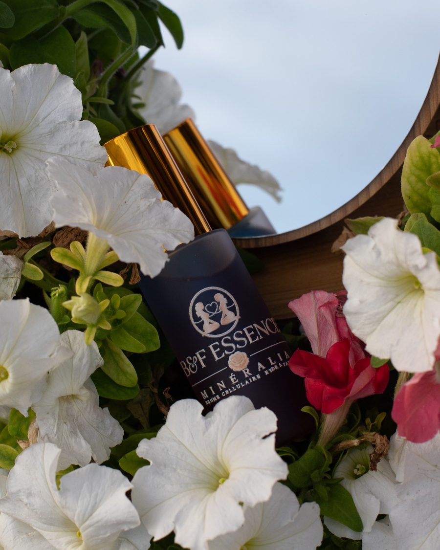 Flacon Minéralia, brume hydratante visage B&F Essence, parmi des pétunias blancs